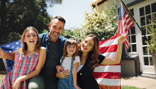 family holding US flag behind their shoulders