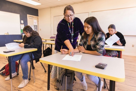 A Navajo woman and high school teacher teaches math to her students in a classroom.