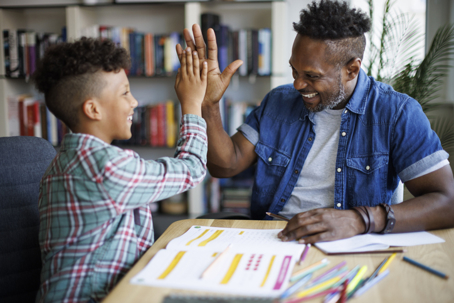 father and son high-fiving while doing homework