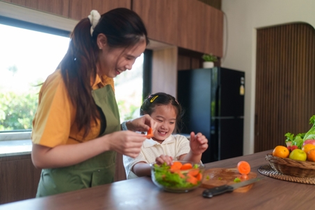 mother and daughter cutting vegetables in the kitchen