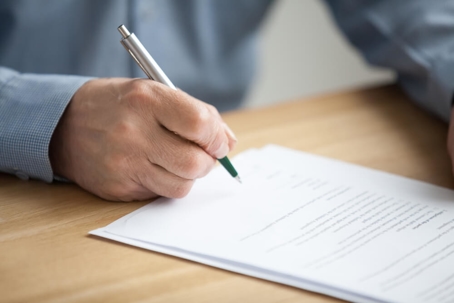 Older male hand signing business document