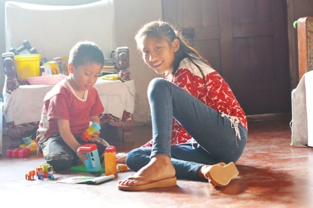 Native American kids playing with plastic blocks in old house.