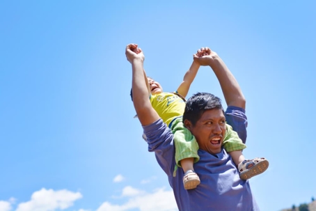 Native american man with his little son on shoulders in the countryside.