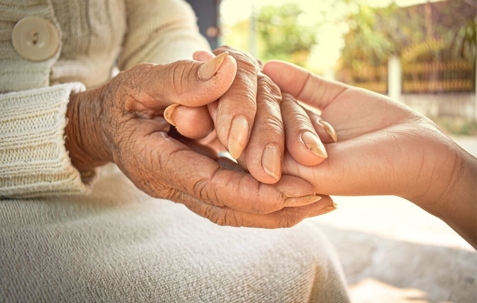 Hands of the old woman and the young woman are close to each other.