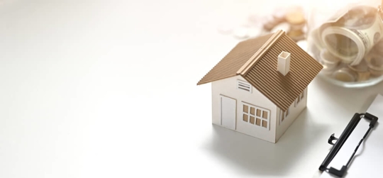 Photo of house model, clipboard, saving money in vase putting together on white table.